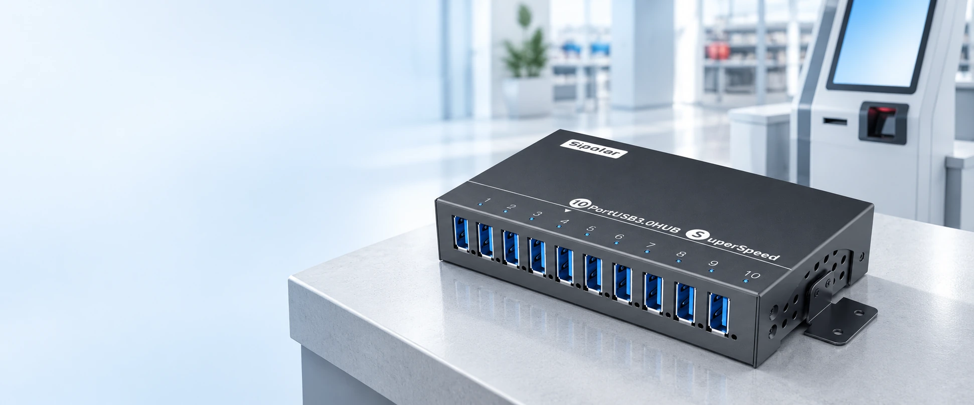 Sipolar A-103 ten-port USB hub on a counter with a self-service terminal in the background